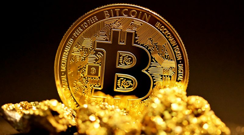 a bitcoin sitting on top of a pile of gold nuggets