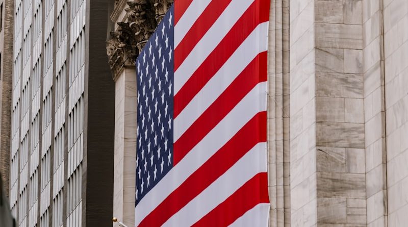 a large american flag hanging from the side of a building
